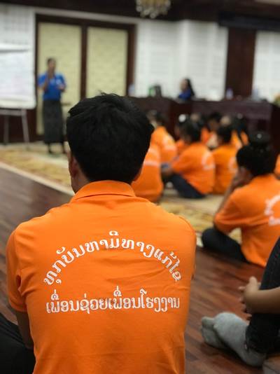 A factory male employee wearing a shirt with the phrase "Every problem has its solution / Friends help friends"
